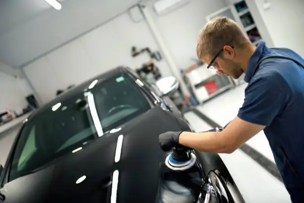 A man is polishing car with an air polisher.