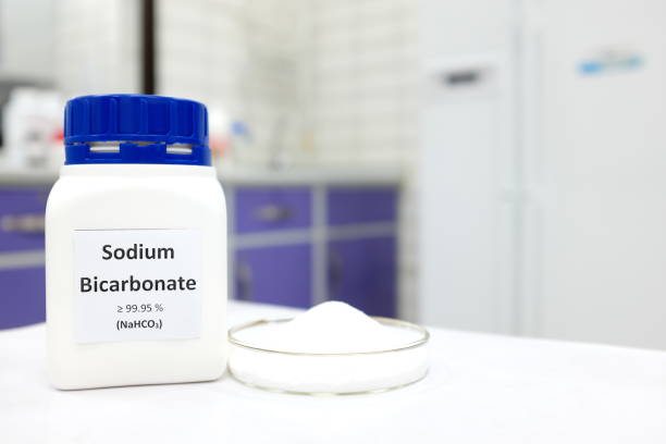 Selective focus of a bottle of sodium bicarbonate chemical compound or baking soda beside a petri dish with solid crystalline powder substance. White Chemistry laboratory background with copy space.